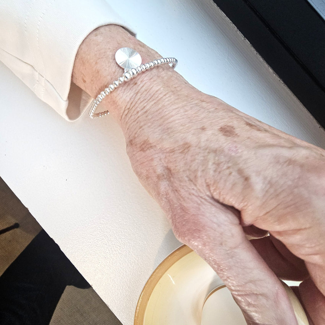 Sterling silver sunburst bracelet with radiant disc charm.