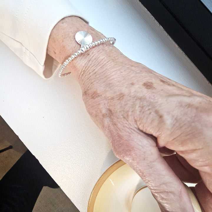 Sterling silver sunburst bracelet with radiant disc charm.