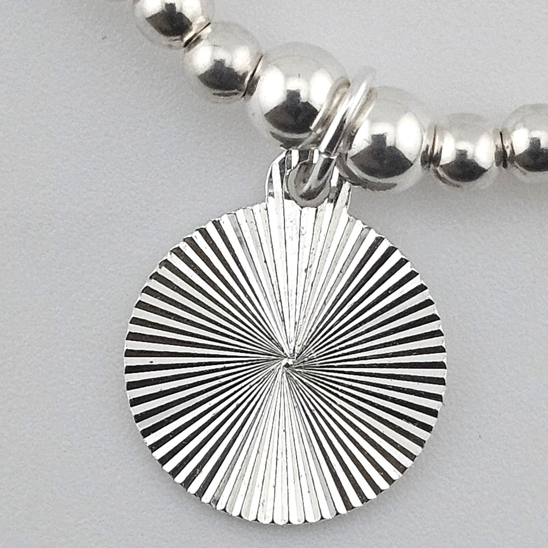 Close-up of sterling silver sunburst charm.
