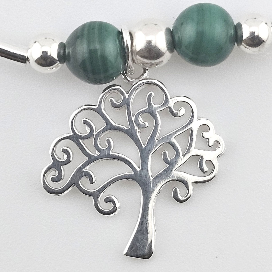 Close-up of Tree of Life charm on silver bracelet.