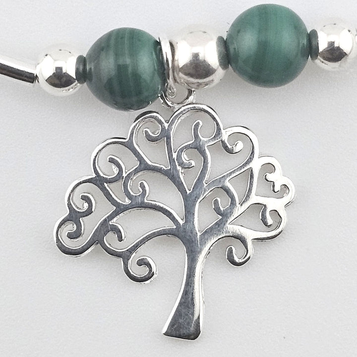 Close-up of Tree of Life charm on silver bracelet.