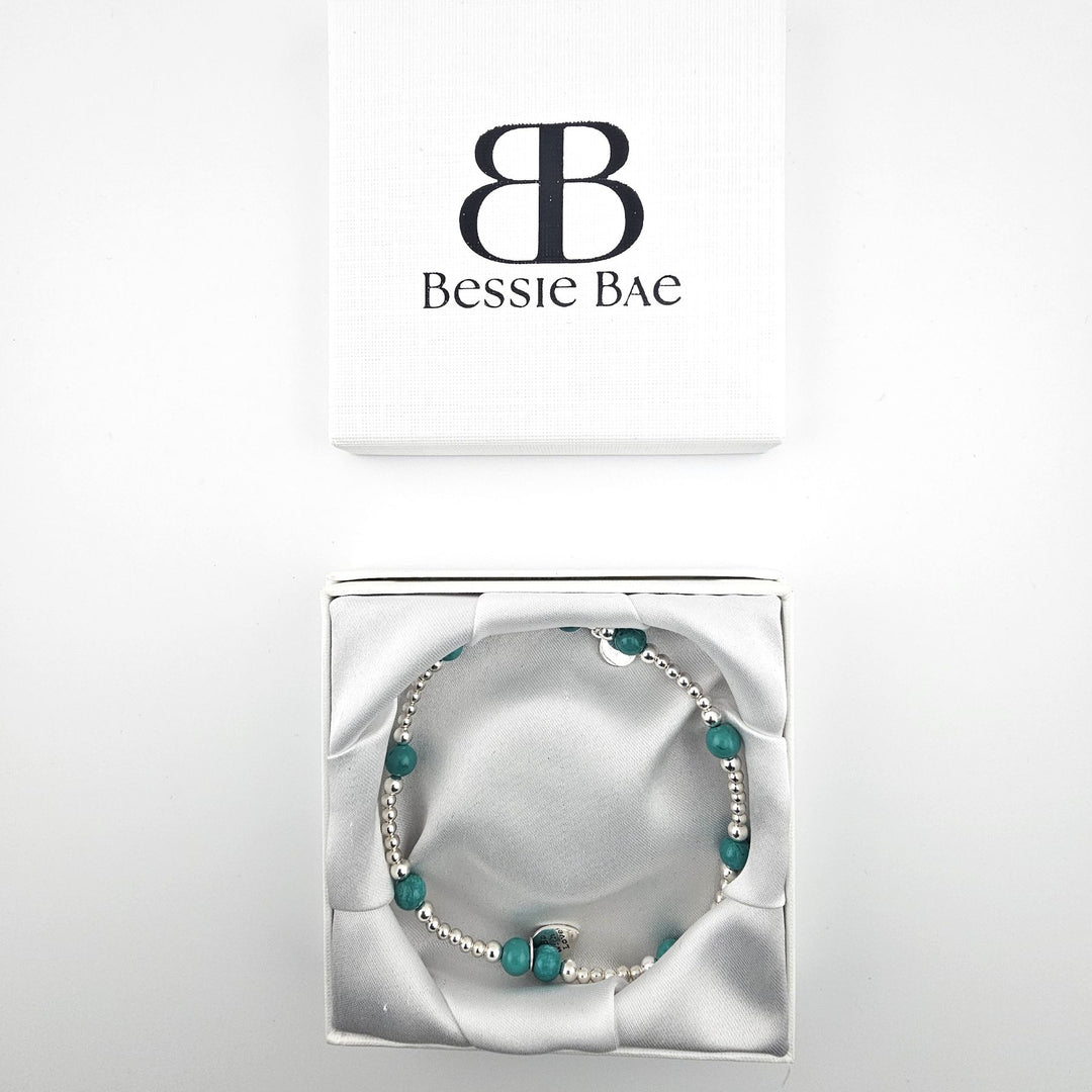 Turquoise and silver anklet with charm beside Bessie Bae packaging.