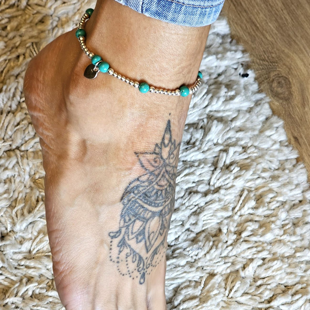 Turquoise and sterling silver anklet with small ‘Made With Love’ charm worn on an ankle.