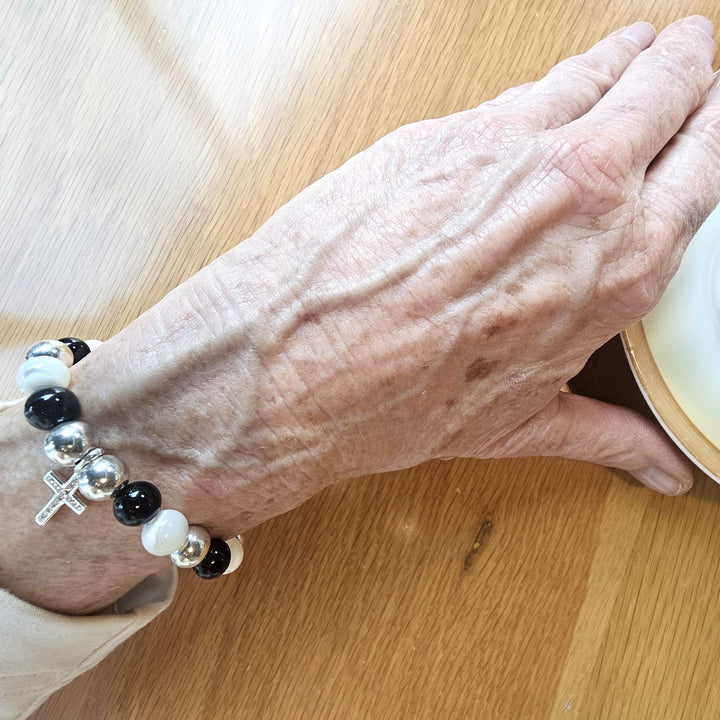 Black Onyx and Mother of Pearl Bracelet with Sterling Silver Cross by Bessie Bae, shown on wrist with alternating gemstone beads and cross charm.