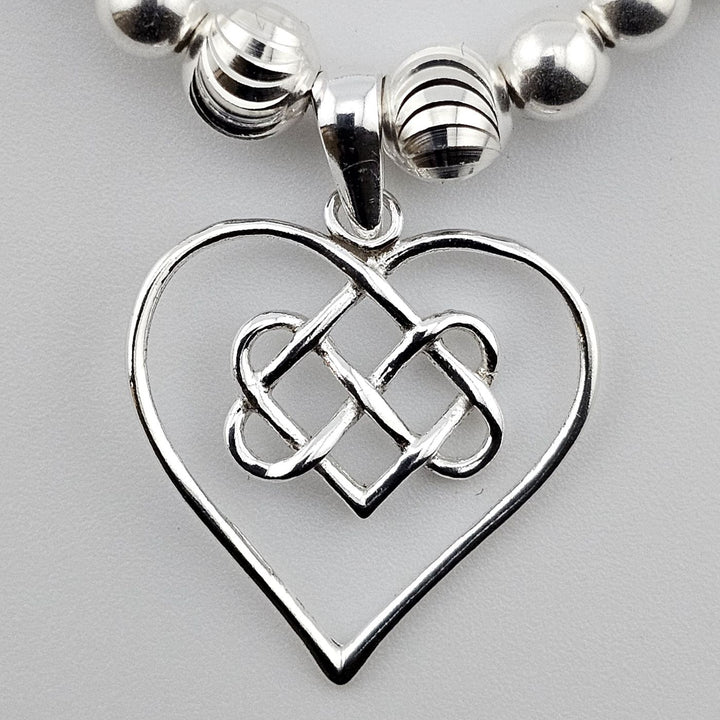 Close-up of Celtic heart charm on sterling silver bracelet.
