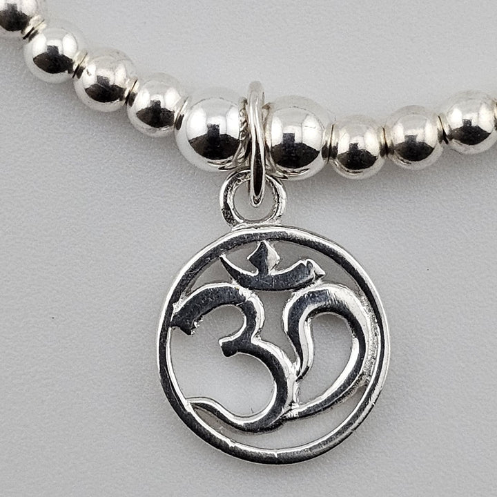 Close-up of sterling silver Om charm on beaded bracelet.