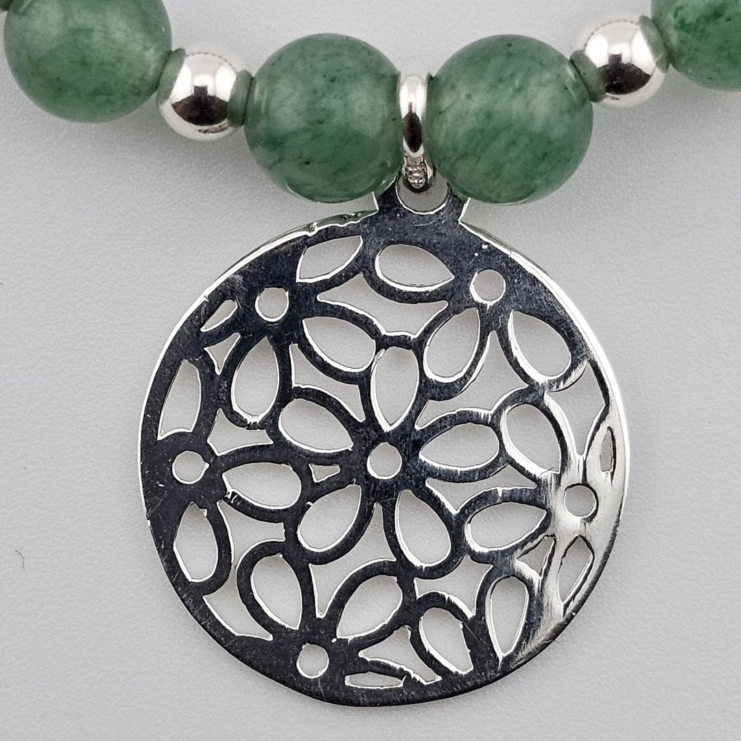 Close-up of sterling silver filigree charm with floral cut-out design.