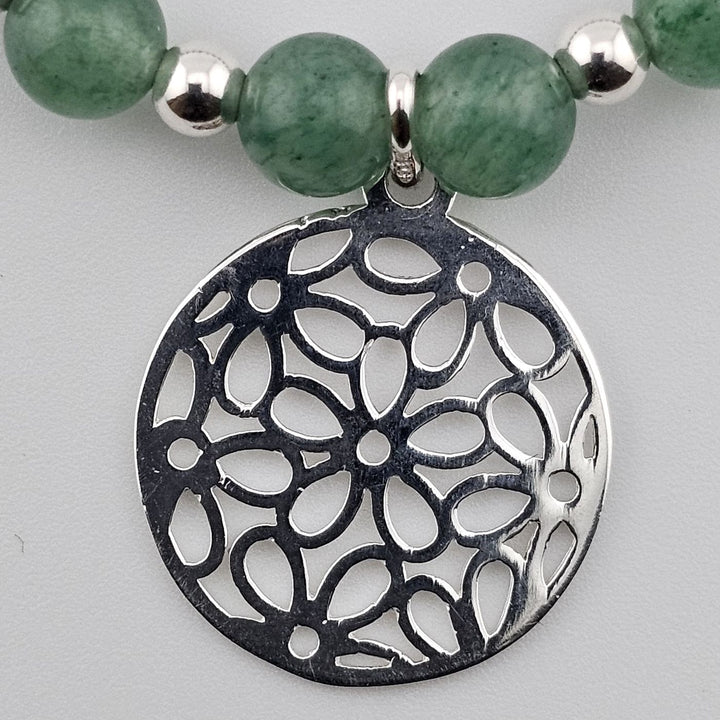 Close-up of sterling silver filigree charm with floral cut-out design.