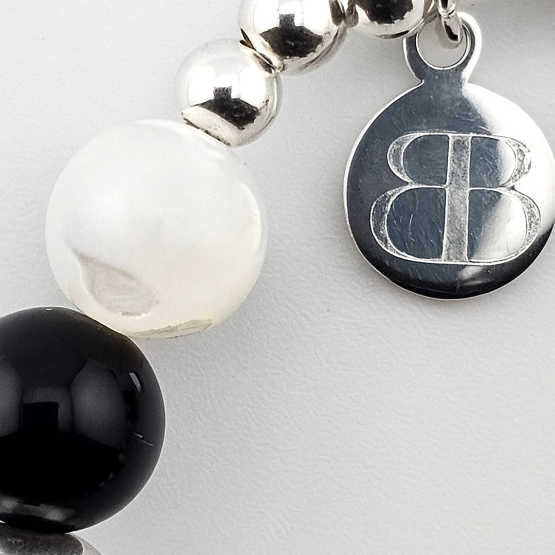 Bessie Bae silver logo tag attached to black onyx and mother of pearl beaded bracelet.