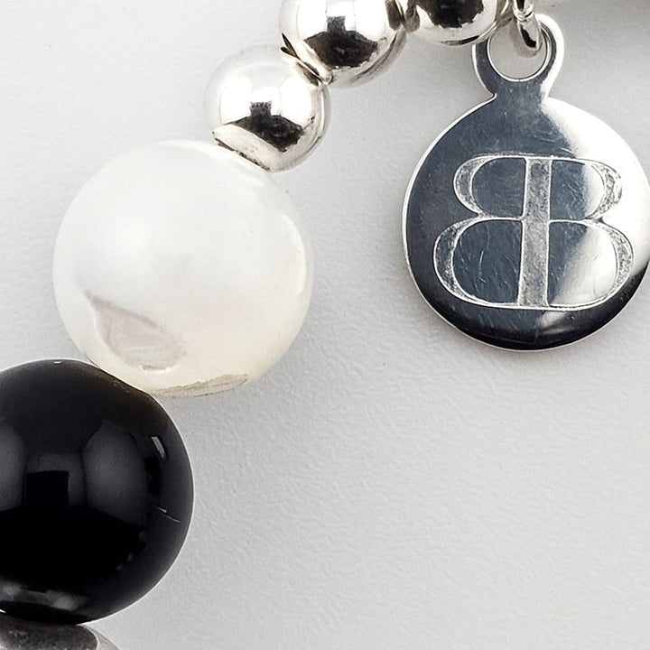 Bessie Bae silver logo tag attached to black onyx and mother of pearl beaded bracelet.