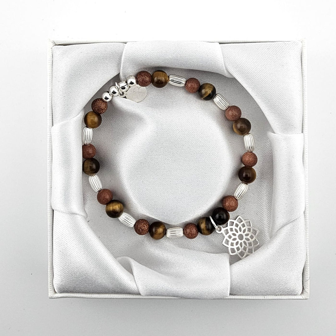 Top view of brown gemstone bracelet with lotus charm in satin presentation box.