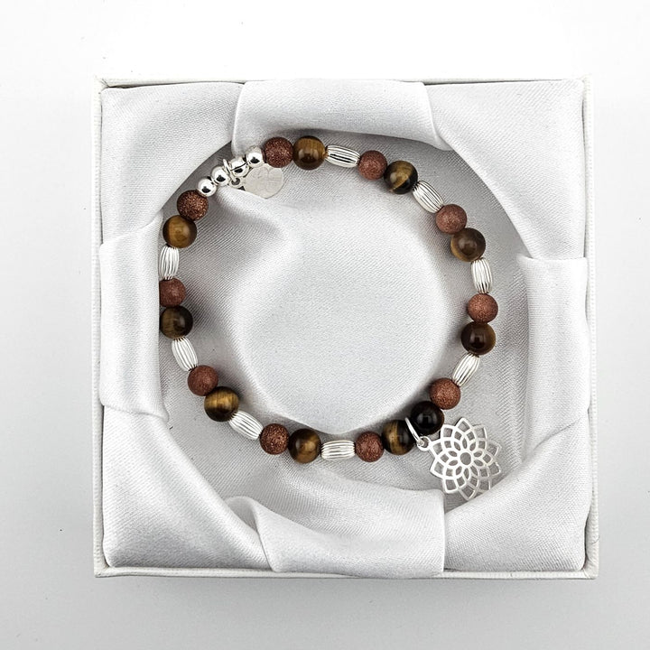 Top view of brown gemstone bracelet with lotus charm in satin presentation box.