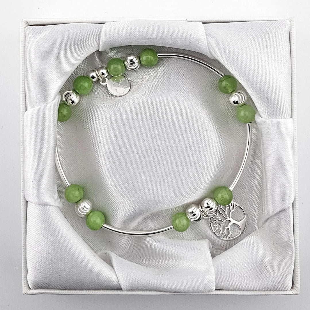 Top view of green aventurine and silver bracelet with Tree of Life charm in satin-lined box.