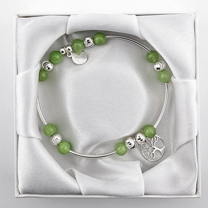 Top view of green aventurine and silver bracelet with Tree of Life charm in satin-lined box.