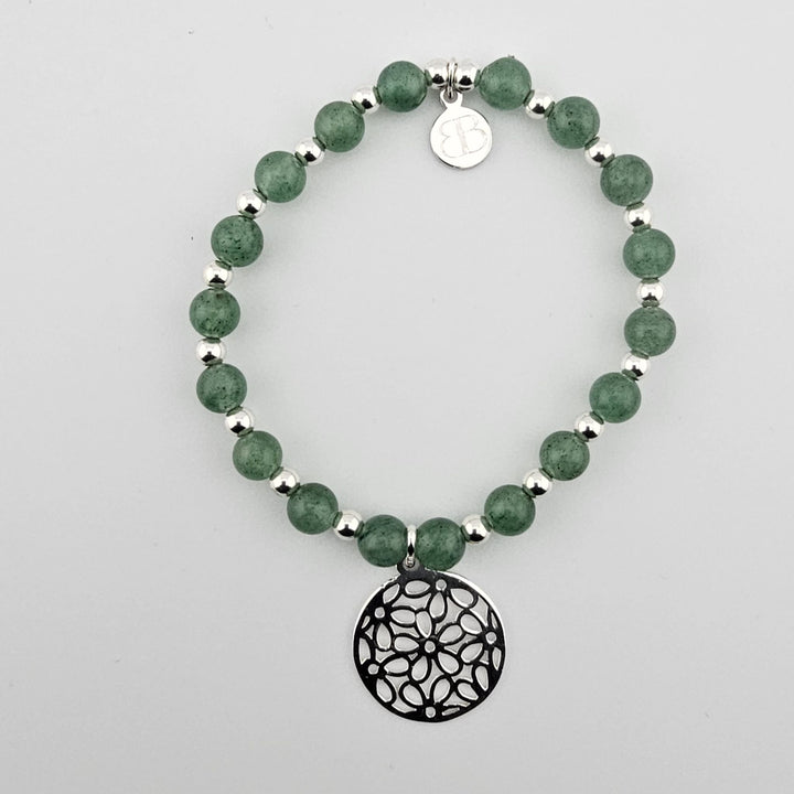 Green aventurine gemstone bracelet with sterling silver filigree charm on white background.