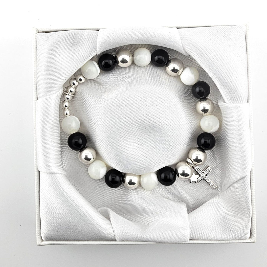 Top view of black and white gemstone bracelet with sterling silver cross and star charms in satin-lined box.