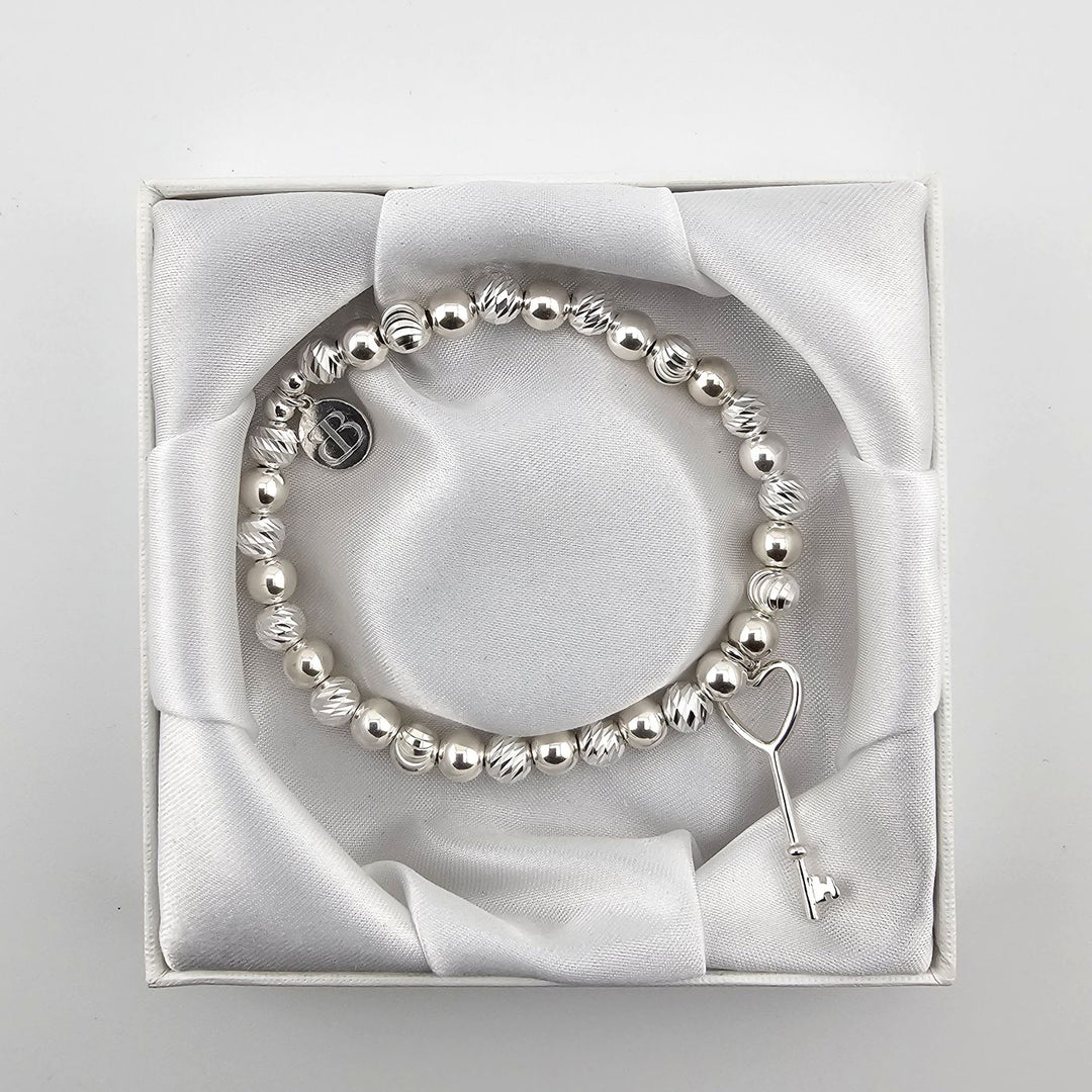 Top view of silver heart key bracelet in satin presentation box.