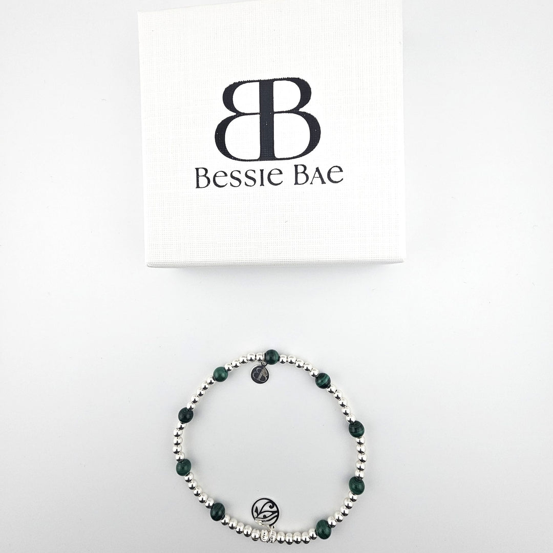 Flatlay of Bessie Bae malachite and sterling silver anklet with branded box.