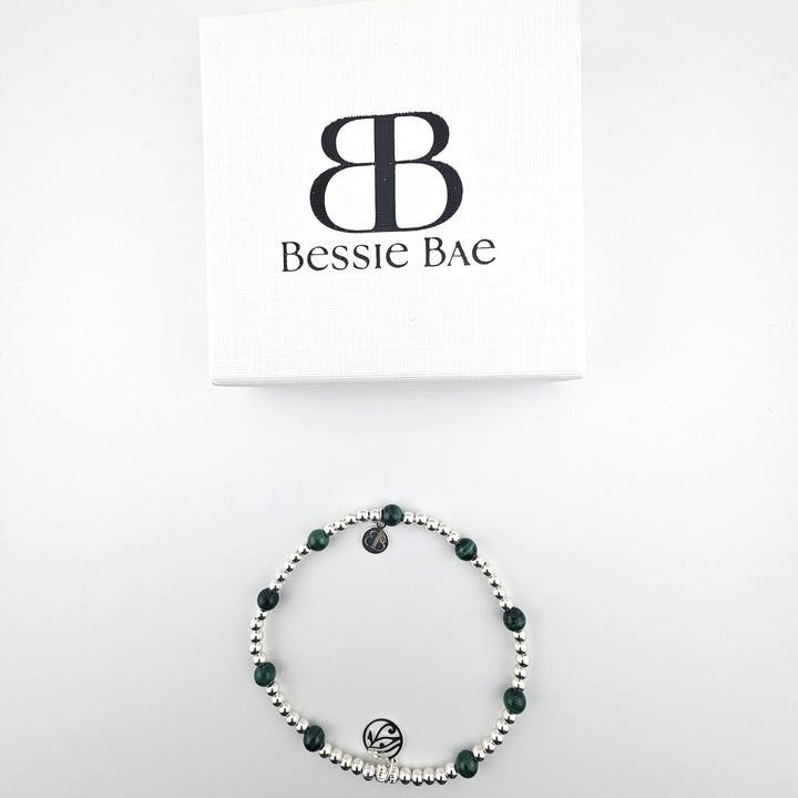 Flatlay of Bessie Bae malachite and sterling silver anklet with branded box.