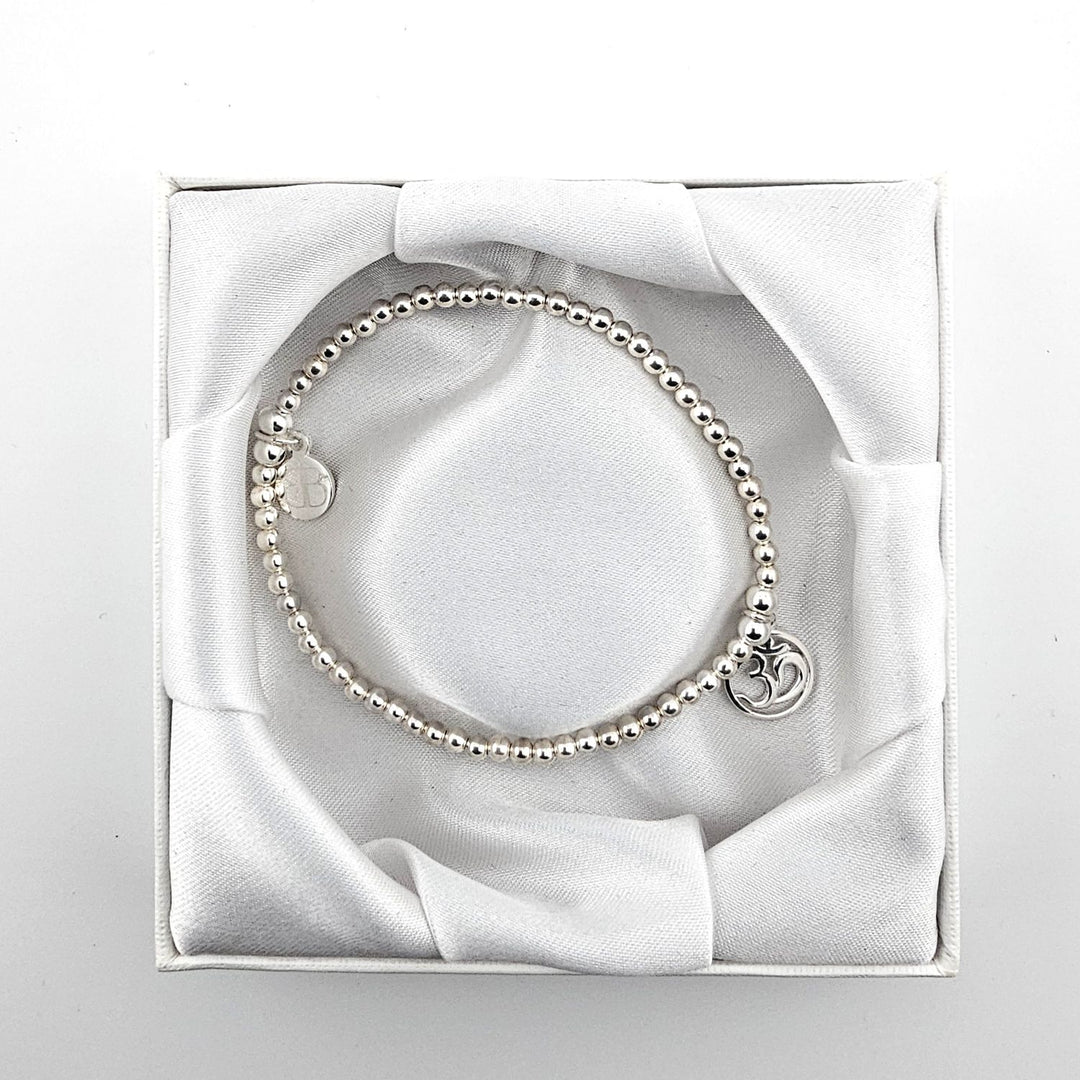 Top view of sterling silver Om symbol bracelet in satin-lined box.