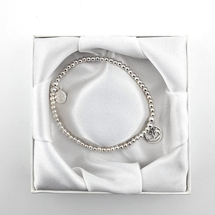 Top view of sterling silver Om symbol bracelet in satin-lined box.