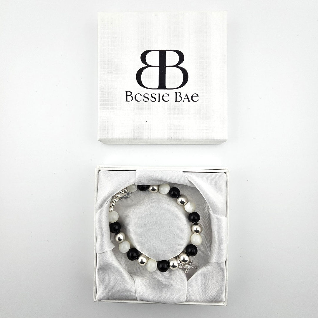 Black onyx and mother of pearl bracelet with silver cross charm presented in Bessie Bae luxury gift box.
