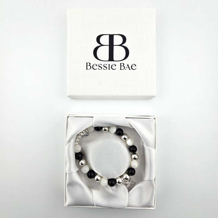Black onyx and mother of pearl bracelet with silver cross charm presented in Bessie Bae luxury gift box.