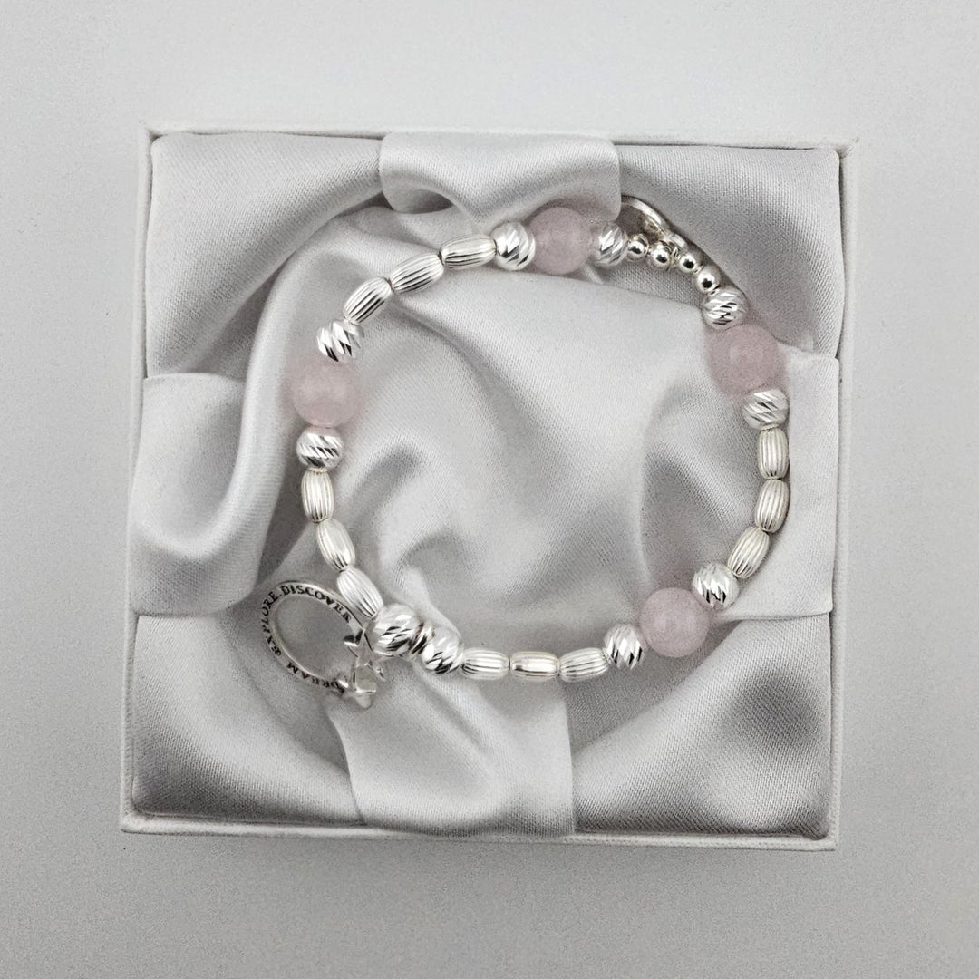 Handcrafted sterling silver beaded bracelet with rose quartz stones and engraved Dream Explore Discover star charm in satin gift box.