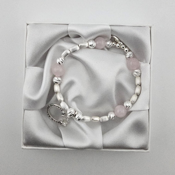 Handcrafted sterling silver beaded bracelet with rose quartz stones and engraved Dream Explore Discover star charm in satin gift box.