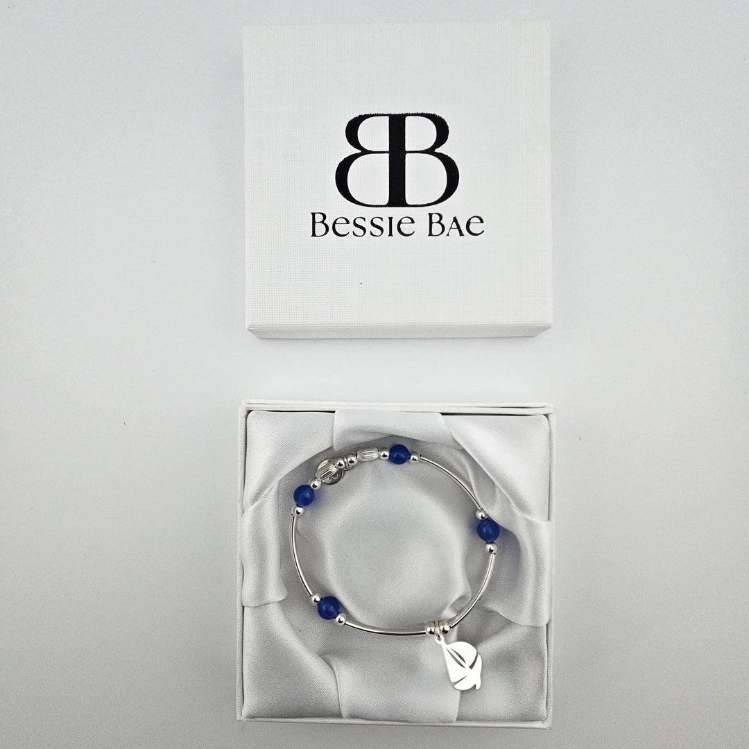 Sterling silver sailboat bracelet with blue beads presented in Bessie Bae gift box.