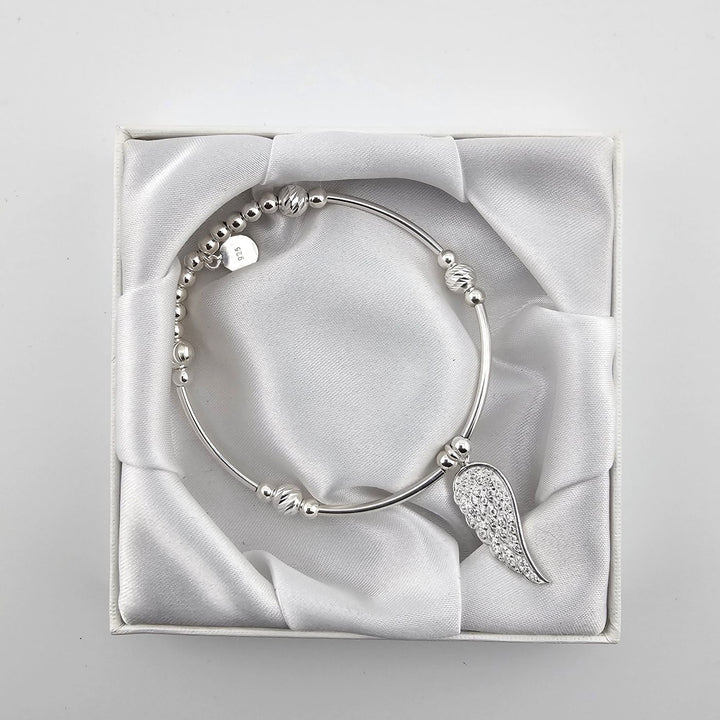 Top view of silver angel wing bracelet in satin-lined white box.