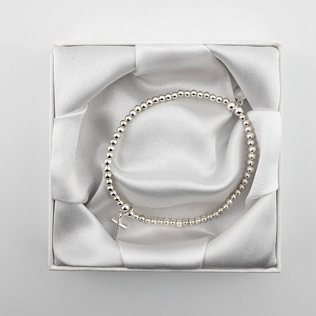 Simple sterling silver beaded bracelet with cross charm in white gift box.