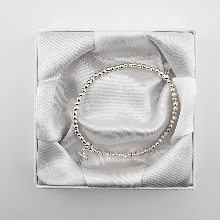 Simple sterling silver beaded bracelet with cross charm in white gift box.