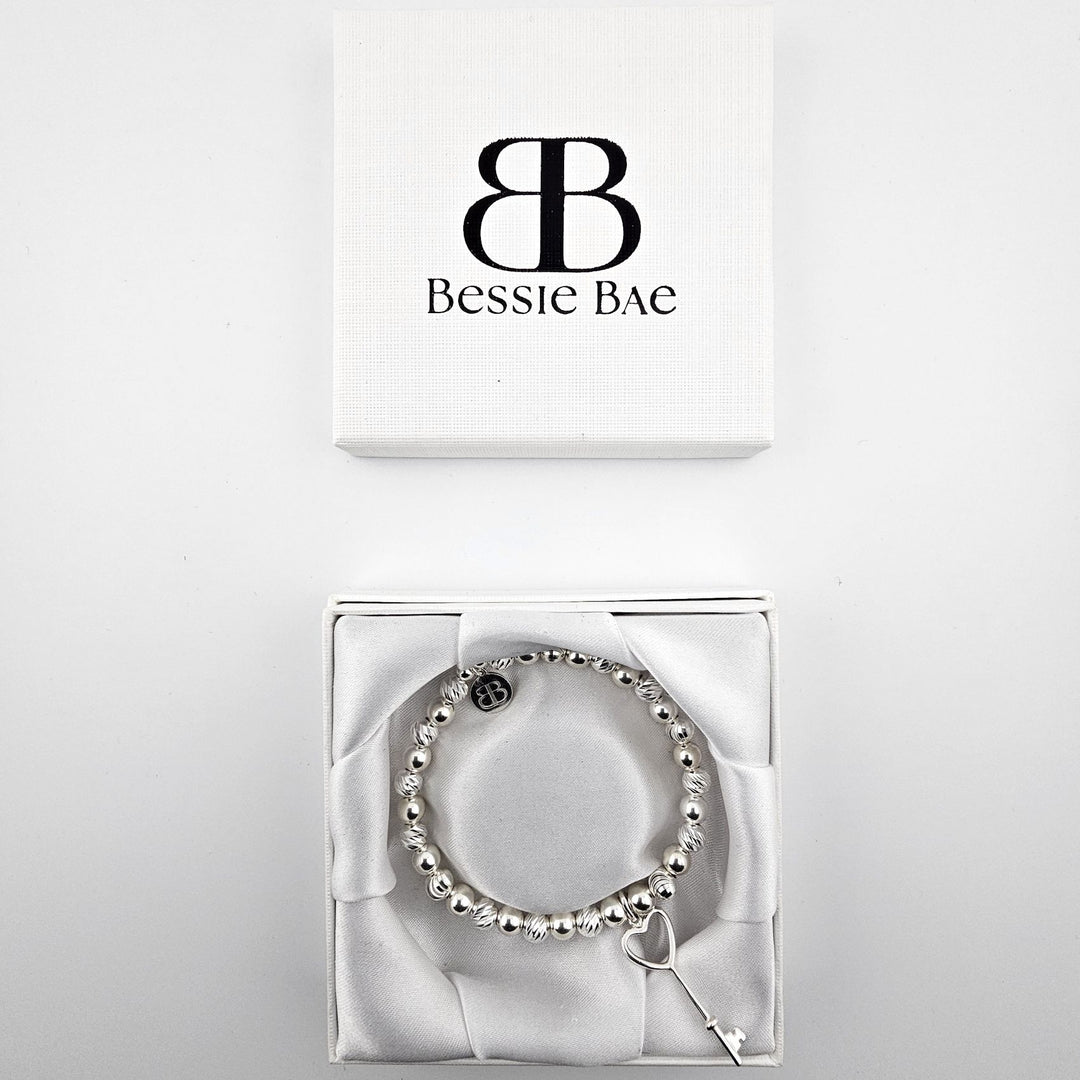 Sterling silver heart key charm bracelet displayed in Bessie Bae gift box.