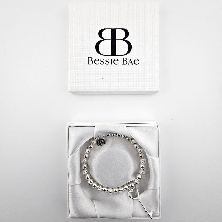 Sterling silver heart key charm bracelet displayed in Bessie Bae gift box.