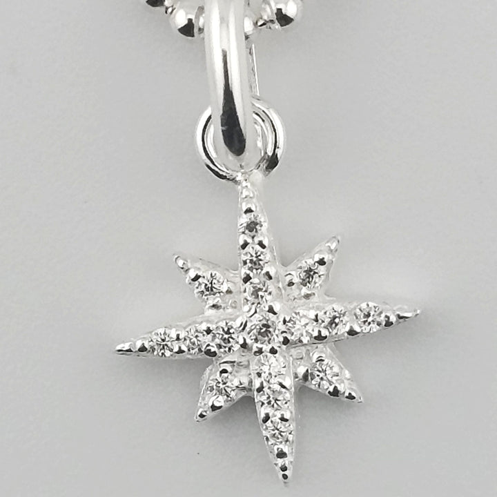 Close-up of sparkling North Star charm on silver necklace.