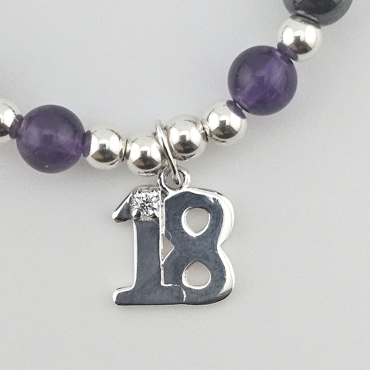 Close-up of Sterling Silver number 18 charm with crystal detail on gemstone bracelet.