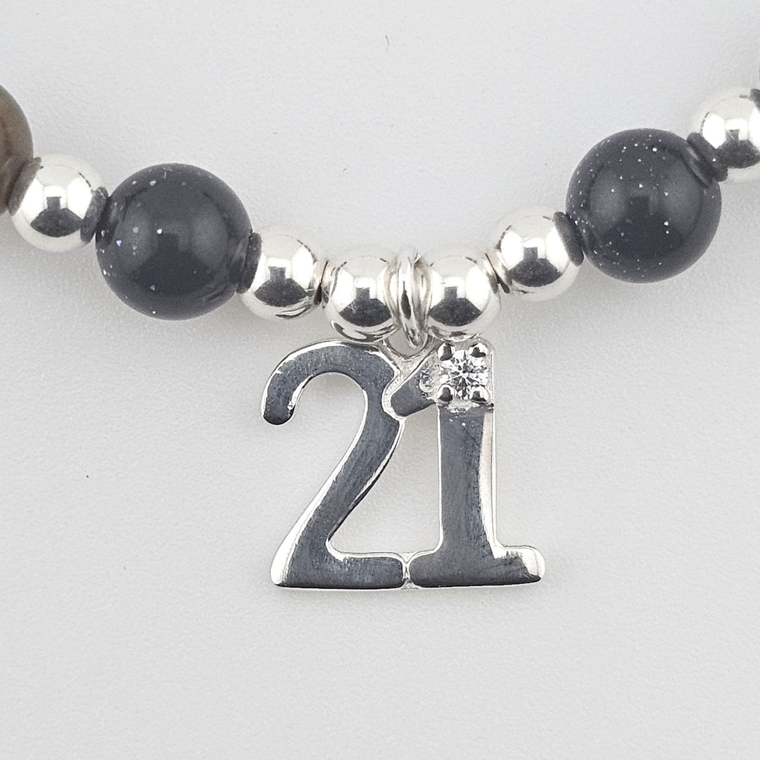 Close-up of number 21 Sterling Silver charm on gemstone bracelet with Tiger’s Eye and Goldstone beads.