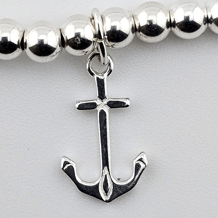 Close-up of polished sterling silver anchor charm on beaded bracelet by Bessie Bae.