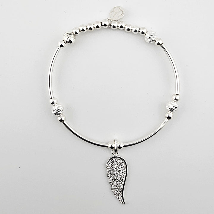 Sterling silver bracelet with sparkling angel wing charm on white background.