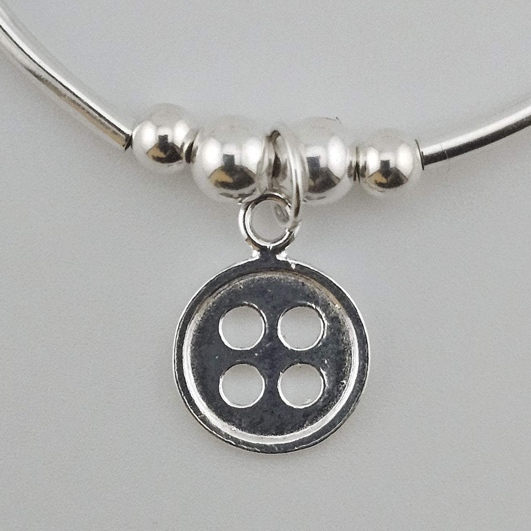 Close-up of Sterling Silver Button charm on bracelet.