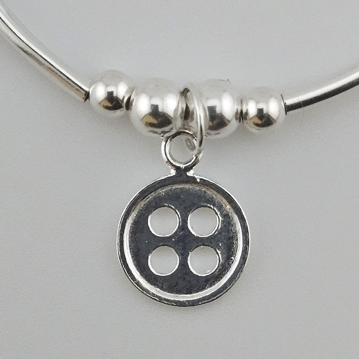 Close-up of Sterling Silver Button charm on bracelet.