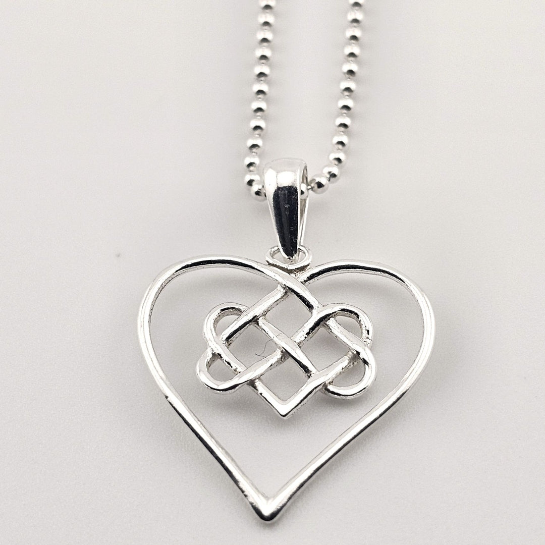 Elegant silver open heart pendant with Celtic knot on chain.