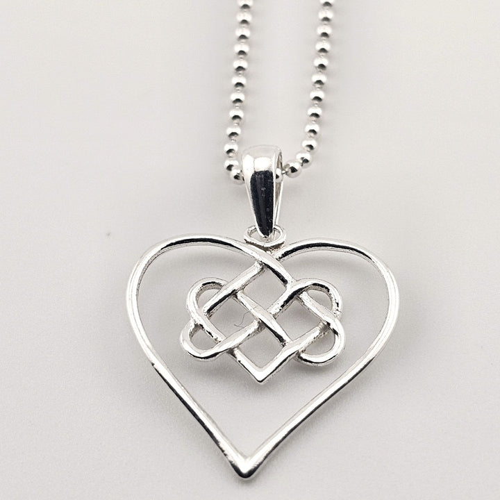 Elegant silver open heart pendant with Celtic knot on chain.