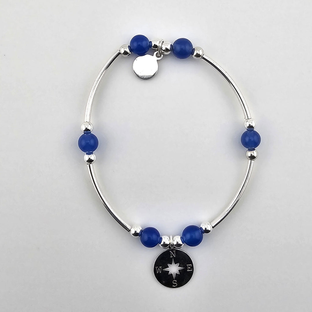 Sterling silver bracelet with blue onyx gemstones and compass charm.