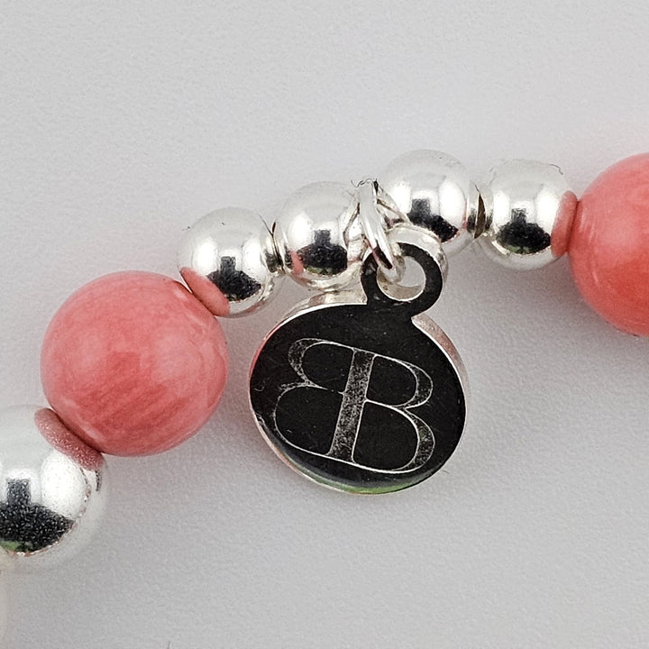 Bessie Bae logo charm with mother of pearl and silver beading detail.