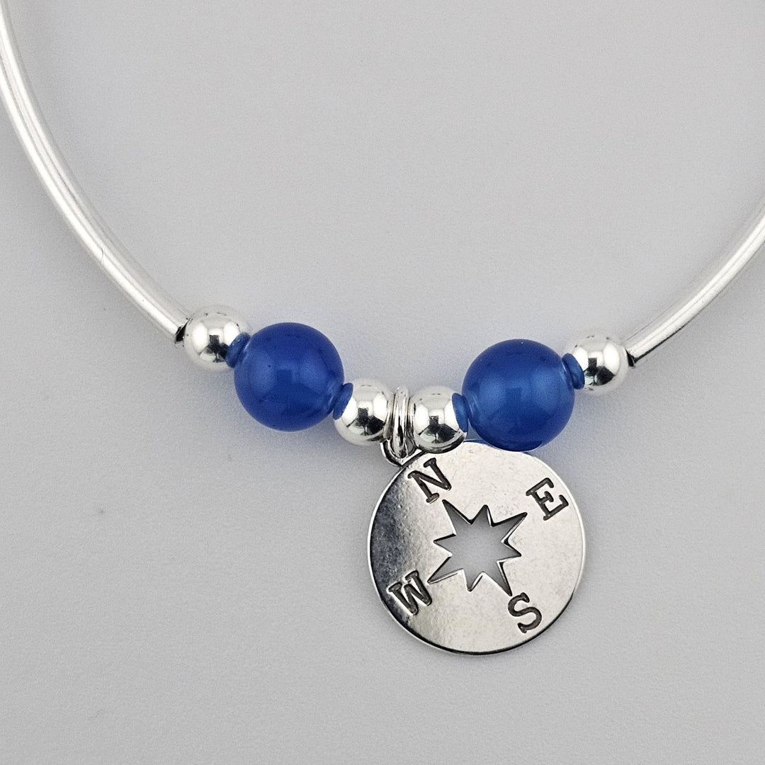 Elegant silver beaded bracelet with blue onyx and compass pendant.