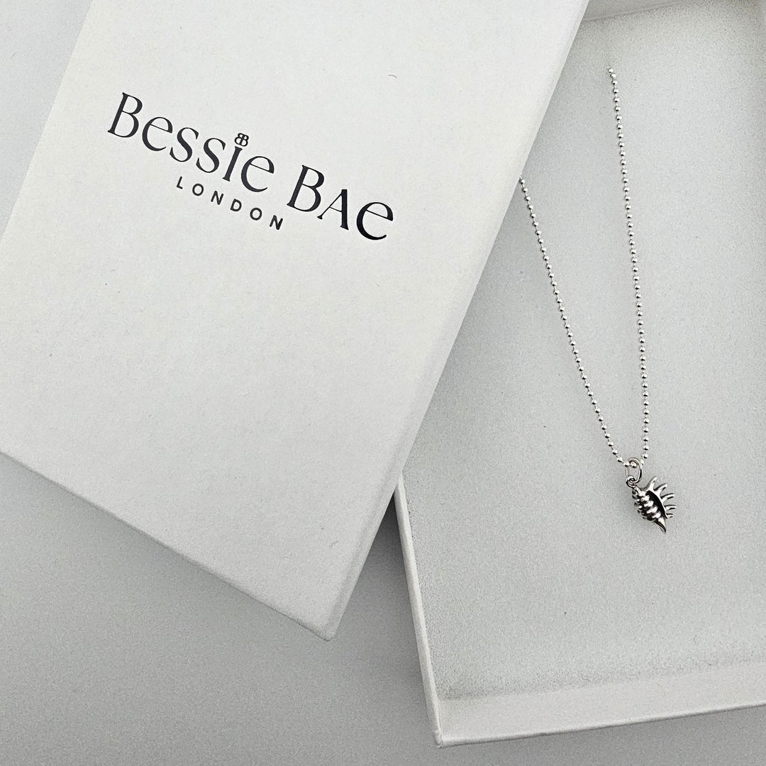 Sterling silver conch shell charm necklace styled with Bessie Bae gift box.