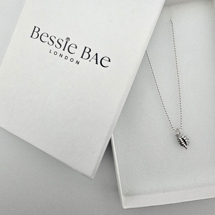 Sterling silver conch shell charm necklace styled with Bessie Bae gift box.