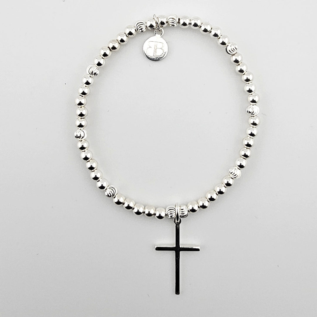 Sterling silver beaded bracelet with polished cross charm on white background.